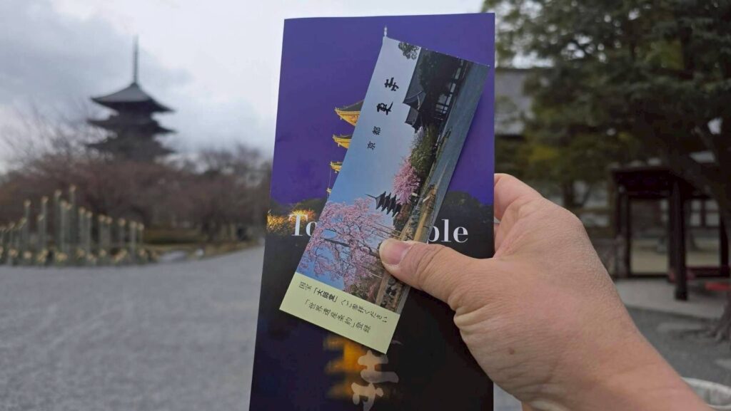 遊客手持京都東寺門票與簡介，背景為著名的五重塔